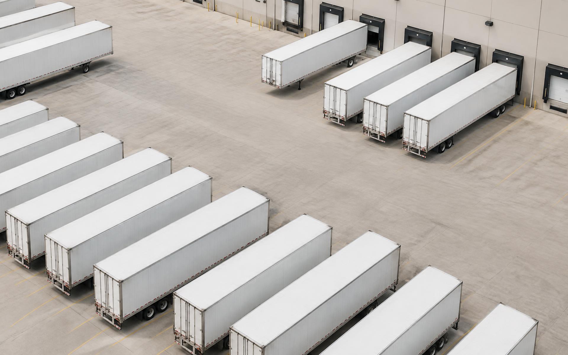 Aerial view of trailers parked in neat rows across a paved commercial yard in daylight